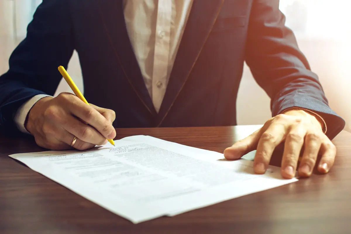 Close up on hand holding a pen and signing paperwork