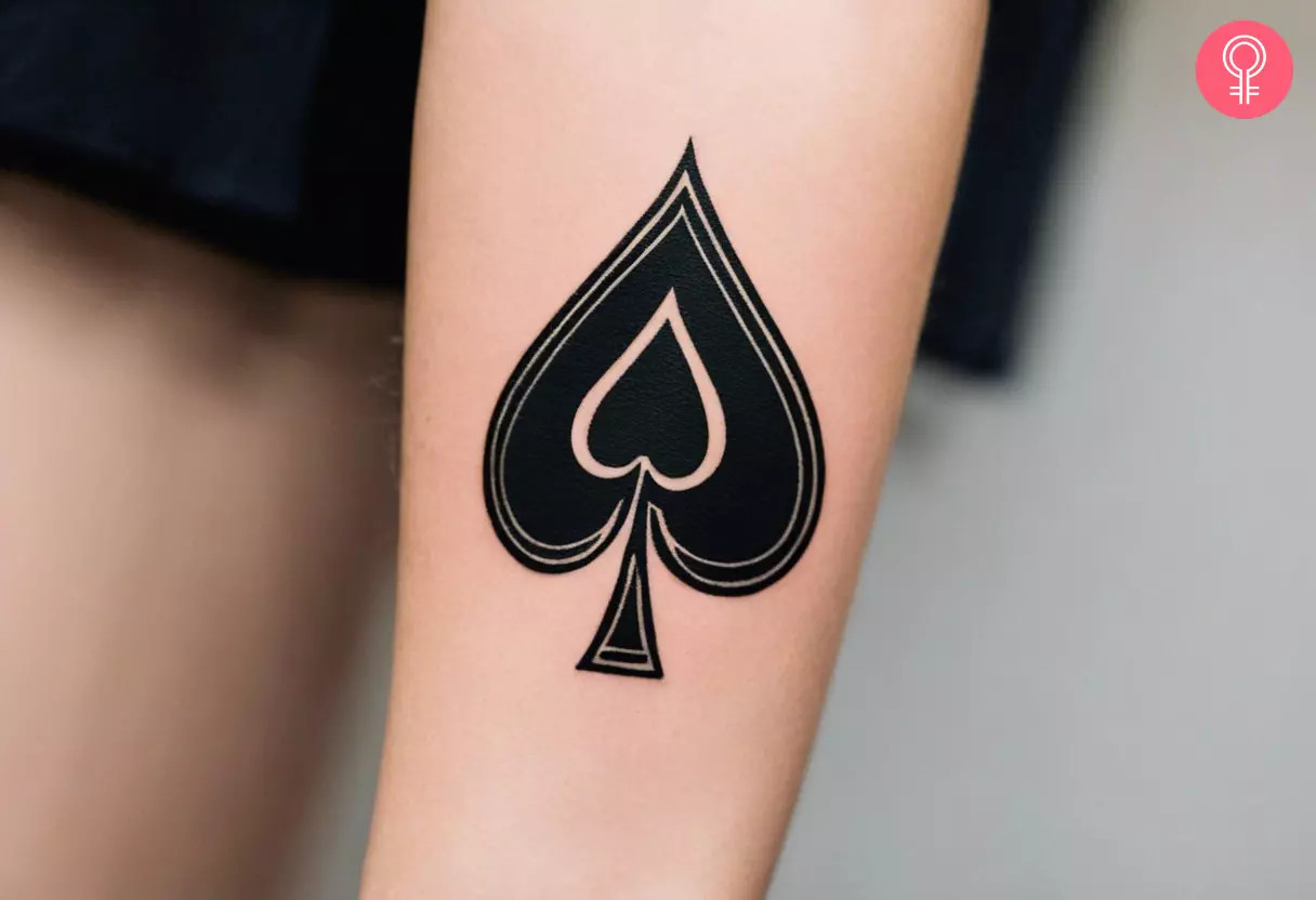 A woman with a minimalist ace of spades tattoo on her arm