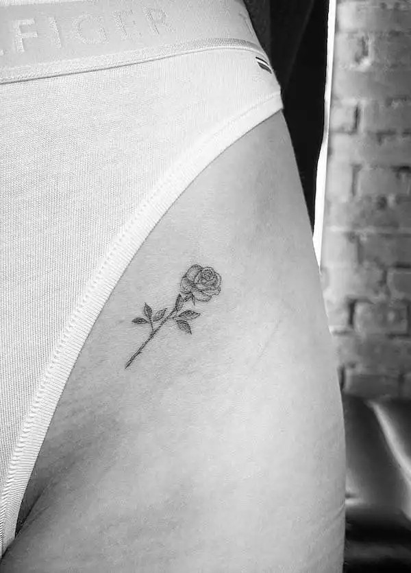 Small rose tattoo on the thigh, by @line.art_.tattoo, representing understated beauty and love