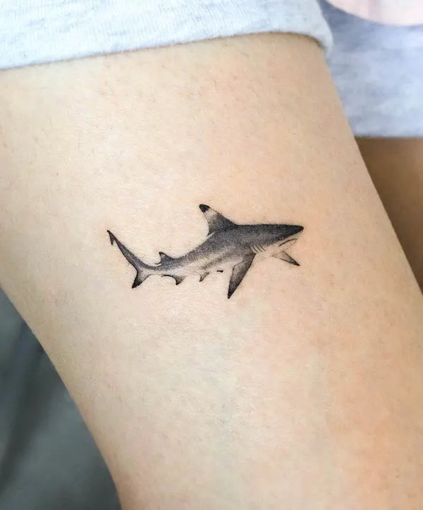 Minimalist shark tattoo on the thigh, by @eunyutattoo, symbolizing strength and resilience