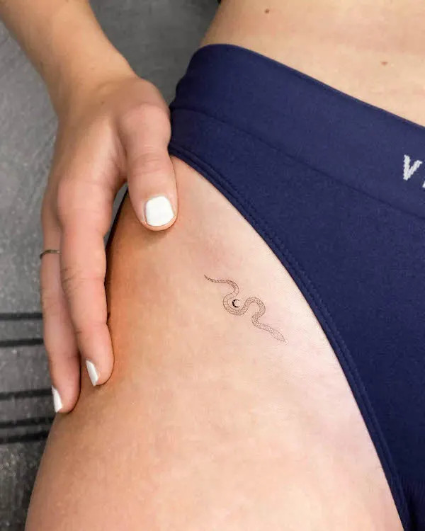 Tiny snake tattoo on the upper thigh, by @little.tattoos, symbolizing mystery and transformation