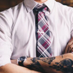 man with a tattoo on his forearm and a suit