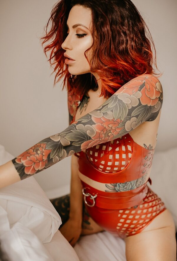 Close-up shot of Adreena Angela's shoulder tattoo by Rodrigo Souto, photographed by Adam Robertson, highlighting the intricate details and bold color palette of the peony design