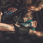 Tattoo artist tattooing a client's arm