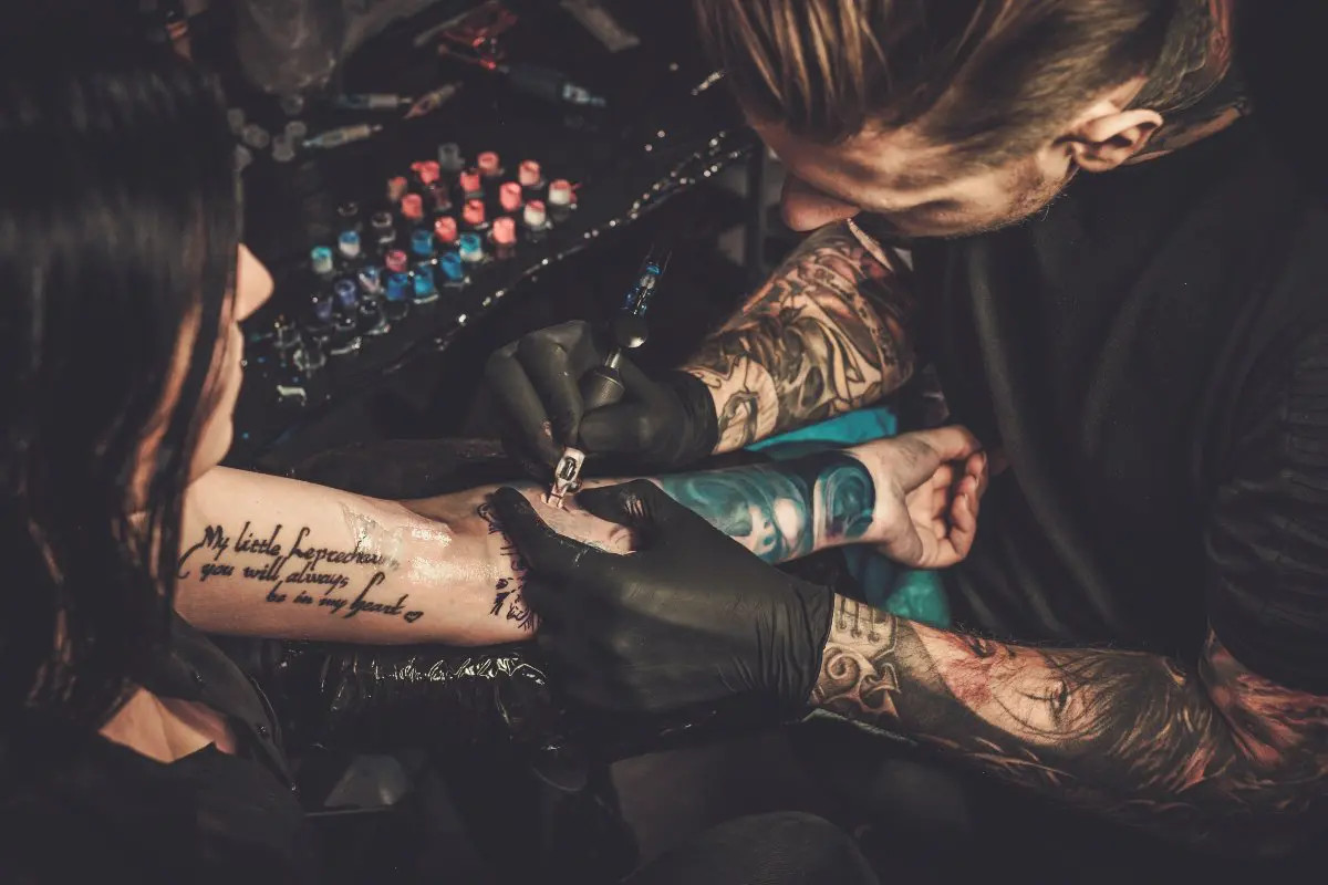 Tattoo artist tattooing a client's arm