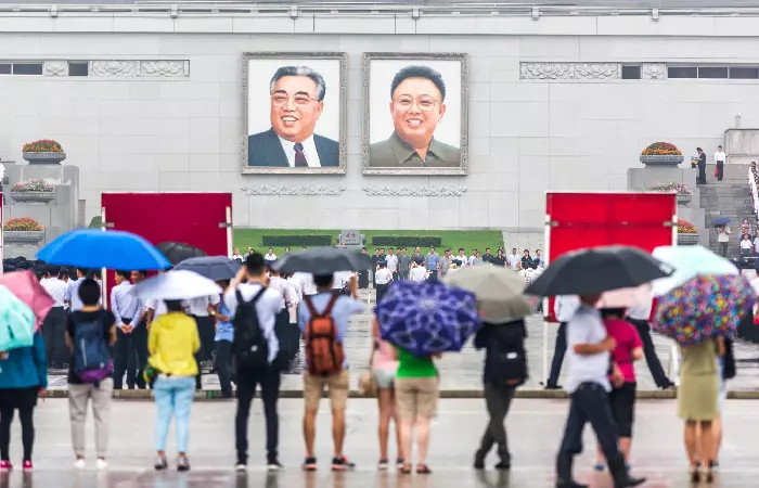 A propaganda poster in North Korea with a political tattoo depicted, highlighting the mandatory adherence to political ideologies.